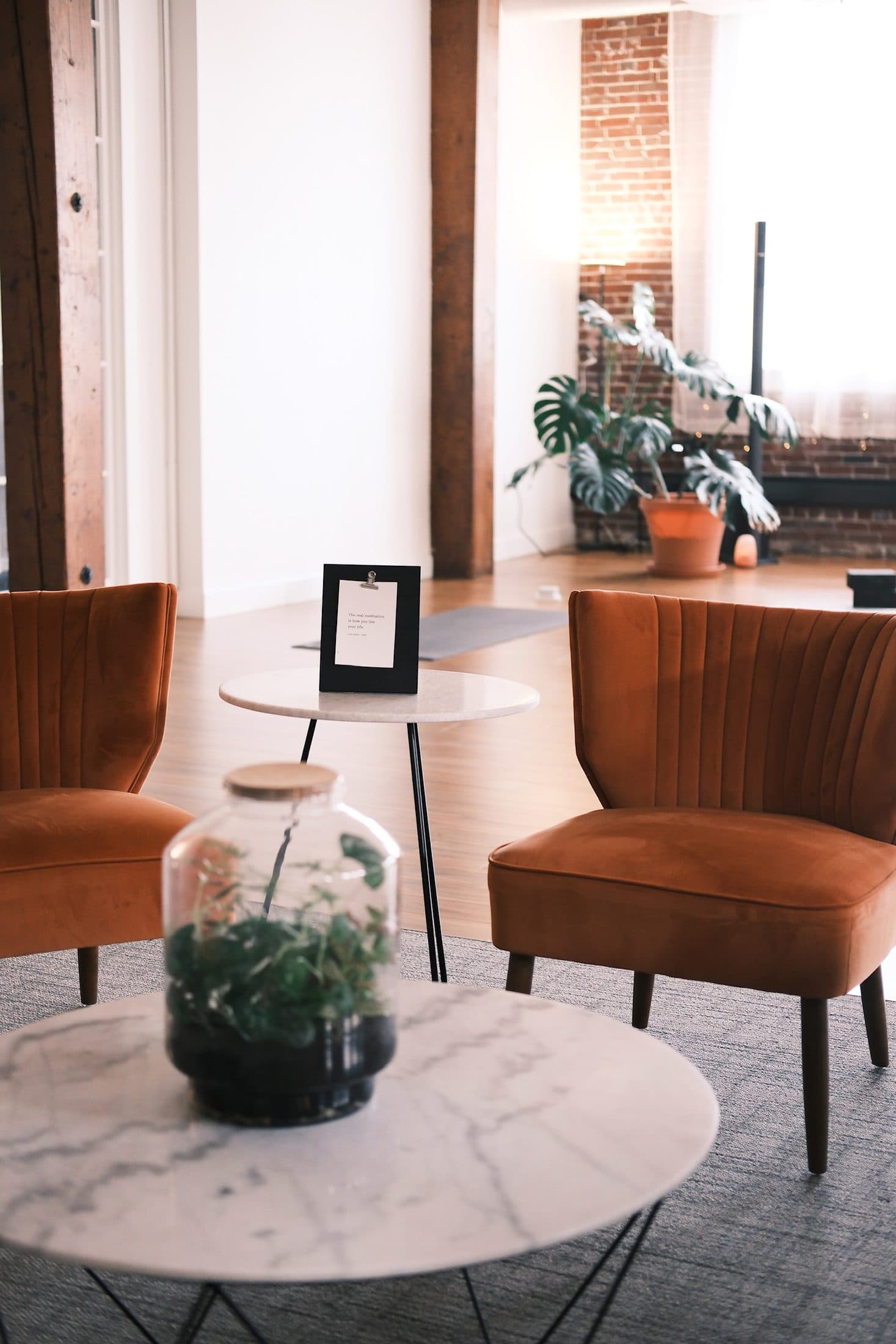 Rust velvet chairs around a marble table holding a glass terrarium