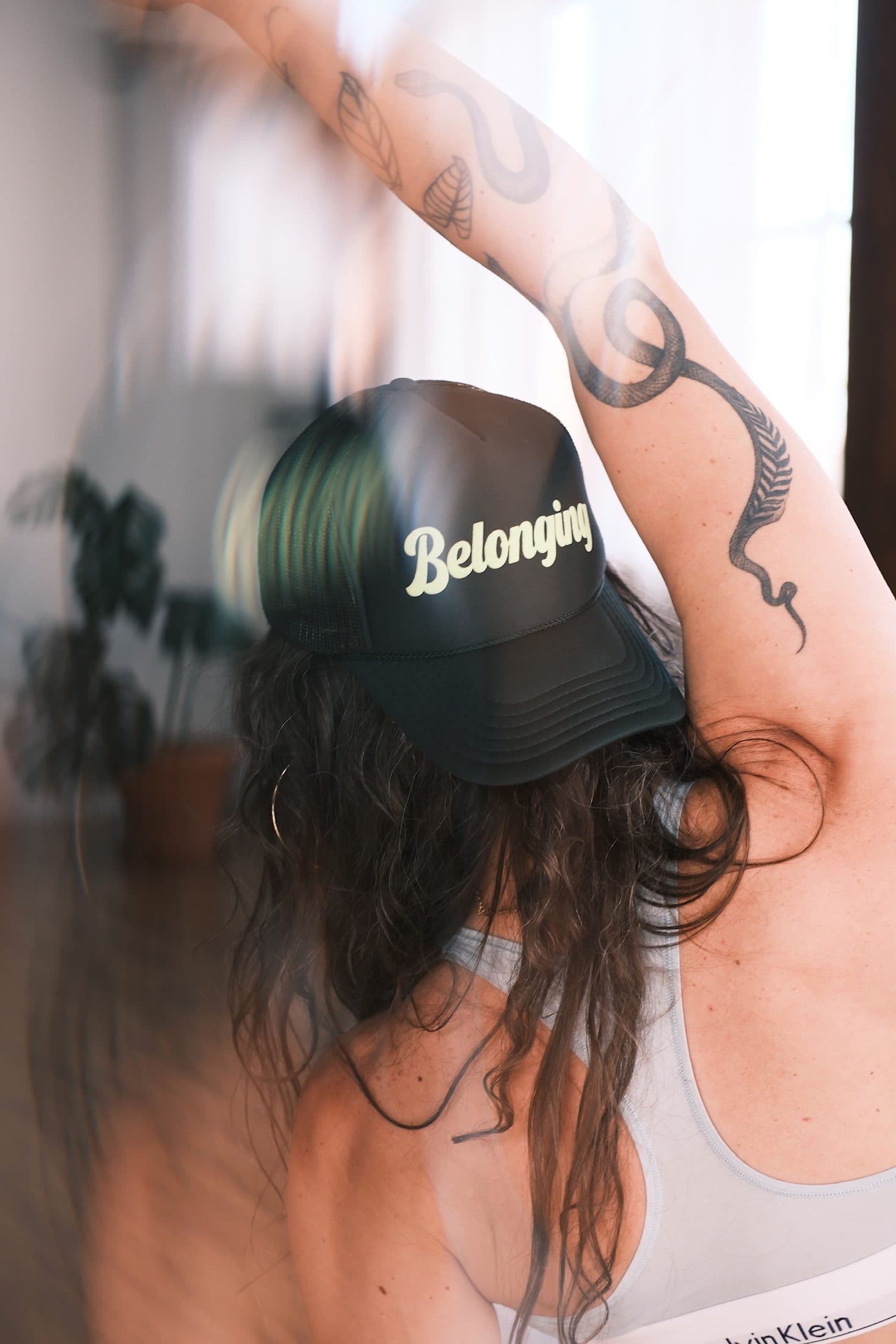 Practitioner from behind, one tattooed arm raised, cap turned backward